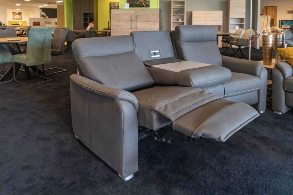Graues Sofa mit elektrischer Relaxfunktion und ausgefahrener Fußstütze im Showroom